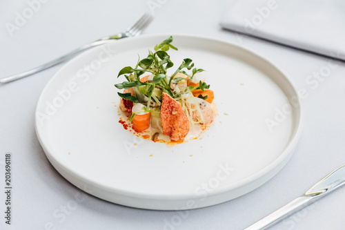 Modern French cuisine: Lobster tail salad including lobster, asparagus and roasted sunflower seeds with white sauce served in white plate. photo