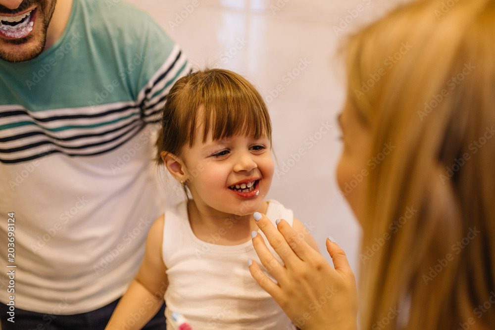Happy family having fun while they are brushing their teeth in bathroom Happy family having fun while they are brushing their teeth in bathroom