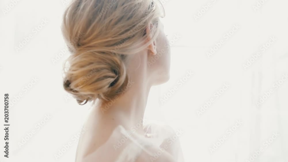 Beautiful bride in a gorgeous dress and bridal veil stands by the window dreaming, smiling charmingly. Happy moments, couple goals, morning of a bride Beautiful bride in a gorgeous dress and bridal veil stands by the window dreaming, smiling charmingly. Happy moments, couple goals, morning of a bride
