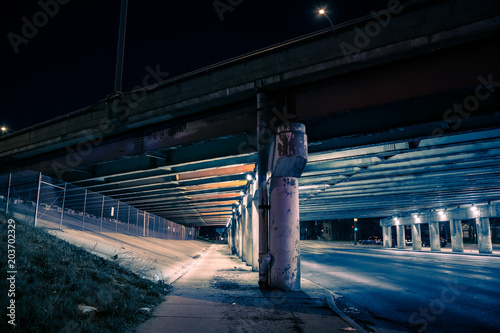 Gritty dark city highway bridge and street underpass at night photo