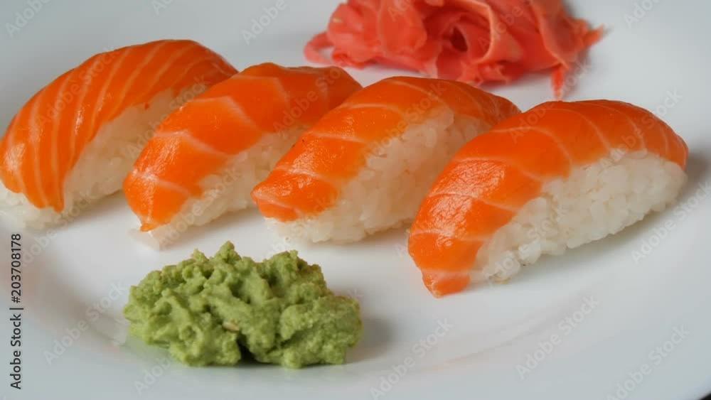 Four large sushi with piece of salmon lie on a large flat plate. Camera zooms Four large sushi with piece of salmon lie on a large flat plate. Camera zooms