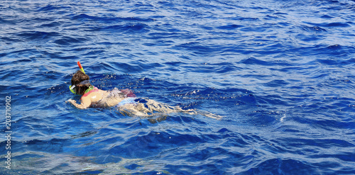 Woman photographer diving into water of Red sea