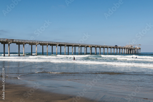 People surf near a concrete research pier at La Jolla Shores in San Diego, California. © sherryvsmith
