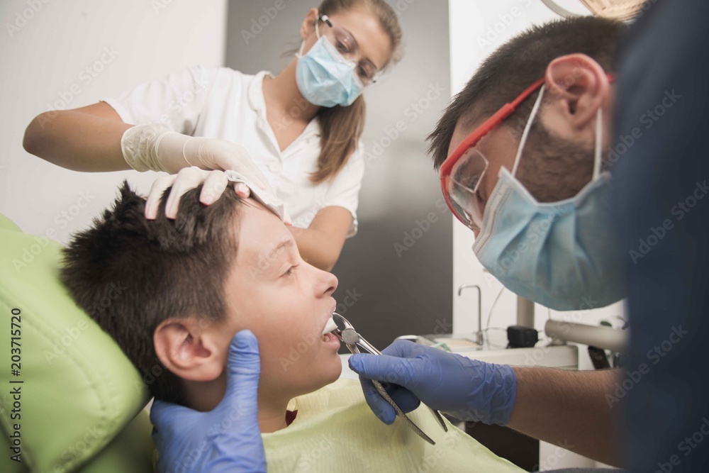 Fototapeta premium Teenager having his tooth removed at the dentist office - oral hygiene health care concept