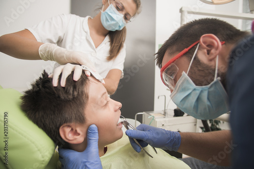 Boy with at the dentist is having his tooth removed and calmed down by a nurse - oral hygiene health care concept