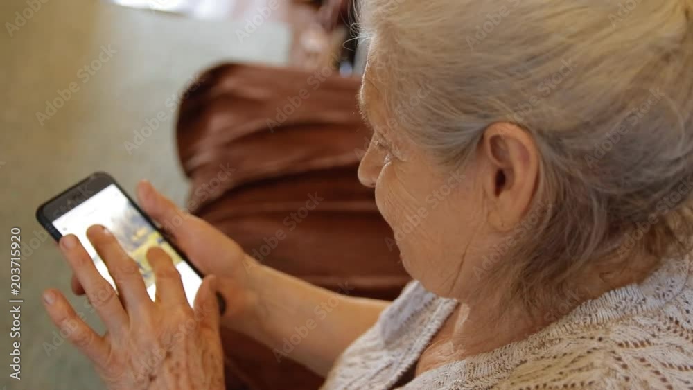Close-up of an old woman using a smartphone to view social networks.