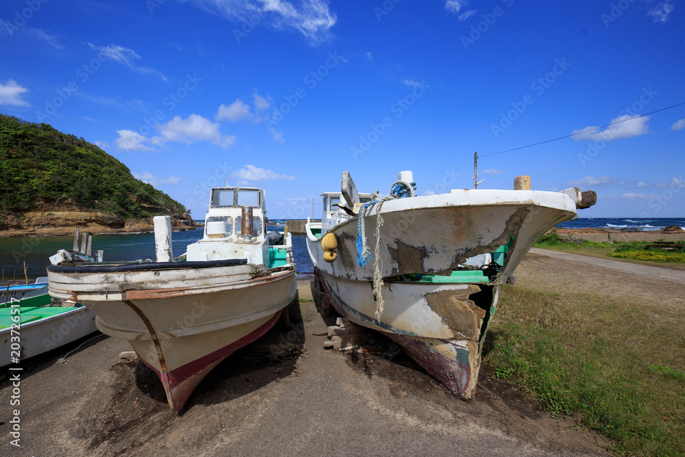 Old Japanese fishing boats sit dockside in a state of disrepair