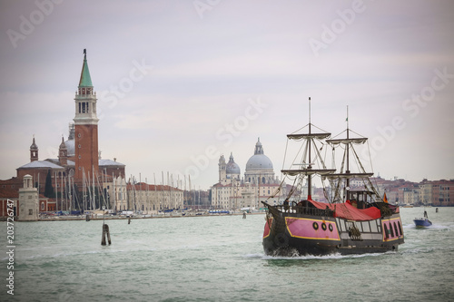 Galley ship sailing in water channel with the Church of San Giorgio Maggiore and Santa Maria della Salute church in the background in Venice, Italy. © Goran Jakus