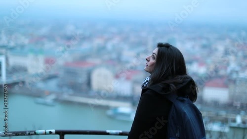 Woman looking down to beautiful scenic landscape vista. Tourist girl visiting european city seen from high above on top of a hiill photo