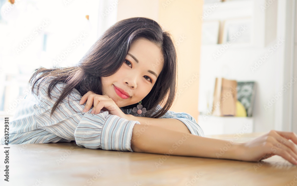 Young Chinese girl sitting in cafe, lying and looking at camera with smile face. Young Chinese girl sitting in cafe, lying and looking at camera with smile face.