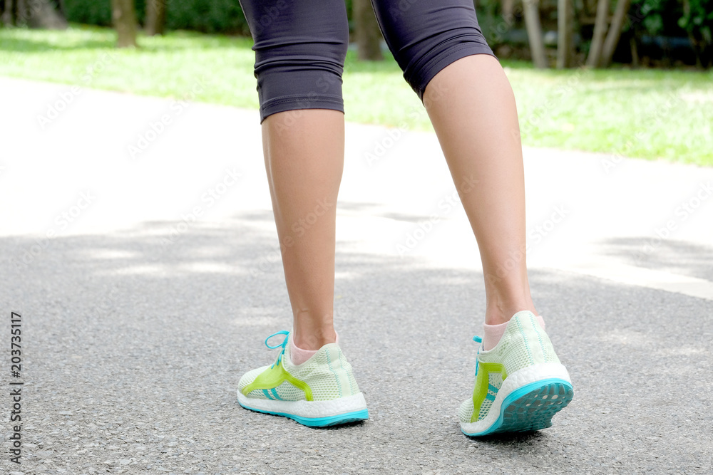 Sport woman walk on  the road which runner athletic by running shoes at the park . Health care and sport concept.