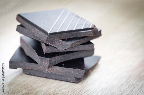 Dark chocolate cut into pieces on wooden floor.Food concept