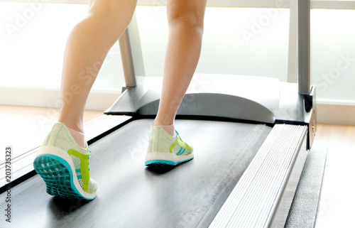leg of woman running on treadmill in the gym which runner athletic by running shoes. Health and sport concept background,