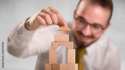 Young handsome businessman using wooden building blocks 