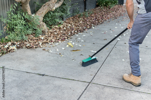 Man sweeping the driveway with a broom photo