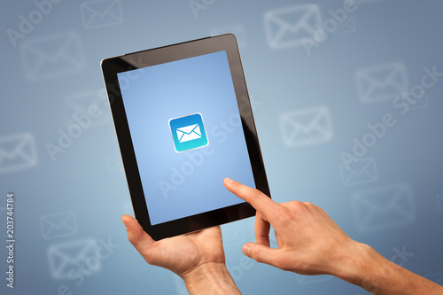 Female fingers touching tablet with mail icon on it 