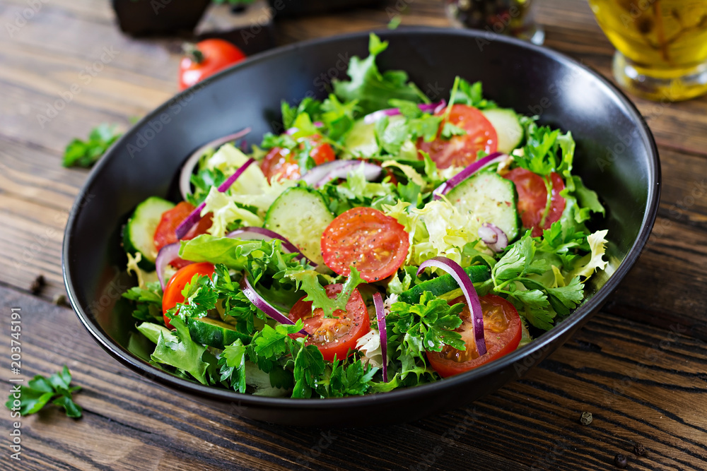 Salad from tomatoes, cucumber, red onions and lettuce leaves. Healthy summer vitamin menu. Vegan vegetable food. Vegetarian dinner table. Salad from tomatoes, cucumber, red onions and lettuce leaves. Healthy summer vitamin menu. Vegan vegetable food. Vegetarian dinner table.