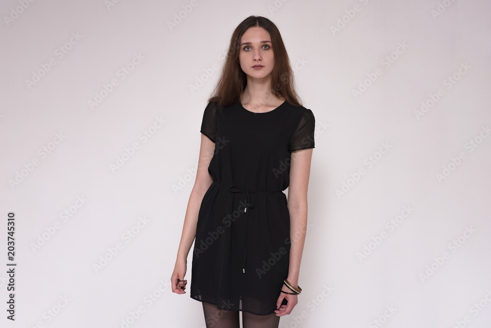 Portrait of a beautiful brunette girl on a gray background in a dress. Portrait of a beautiful brunette girl on a gray background in a dress.
