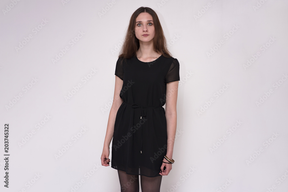 Portrait of a beautiful brunette girl on a gray background in a dress. Portrait of a beautiful brunette girl on a gray background in a dress.