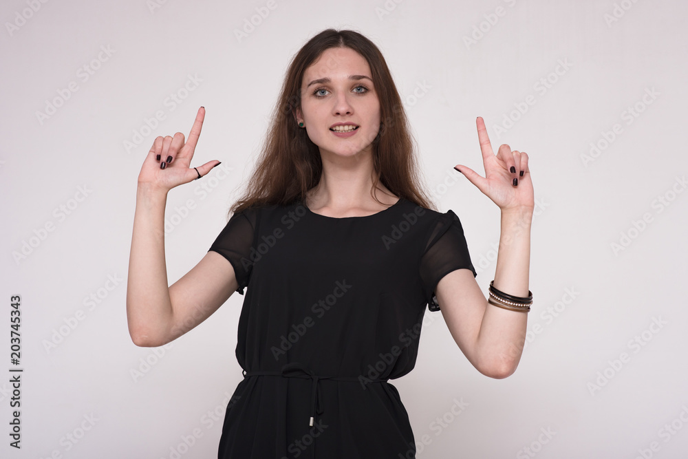 Portrait of a beautiful brunette girl showing thumbs up on a gray background Portrait of a beautiful brunette girl showing thumbs up on a gray background