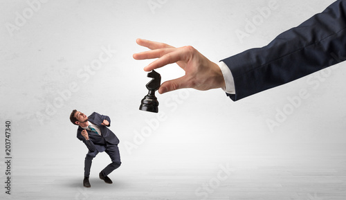 Big hand holding chessman and down little afraid businessman concept in a light space 