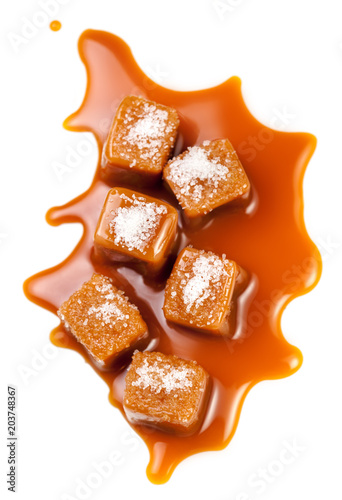 Isolated caramel. Salted Caramel candies pieces  and topping sauce  isolated on white background. Flat lay. Food concept.
