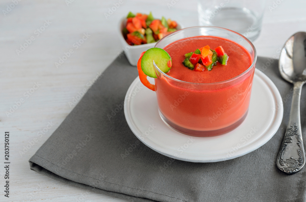 Gazpacho, tomato cold soup made from raw blended vegetables. Traditional Spanish cold soup in glass bowl on wooden table.Copy space Gazpacho, tomato cold soup made from raw blended vegetables. Traditional Spanish cold soup in glass bowl on wooden table.Copy space