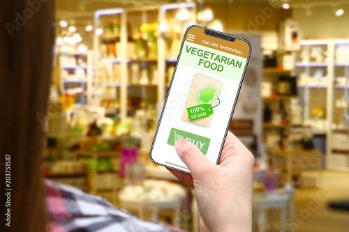 Vegetarian food idea, girl with frameless phone on blurred shop background