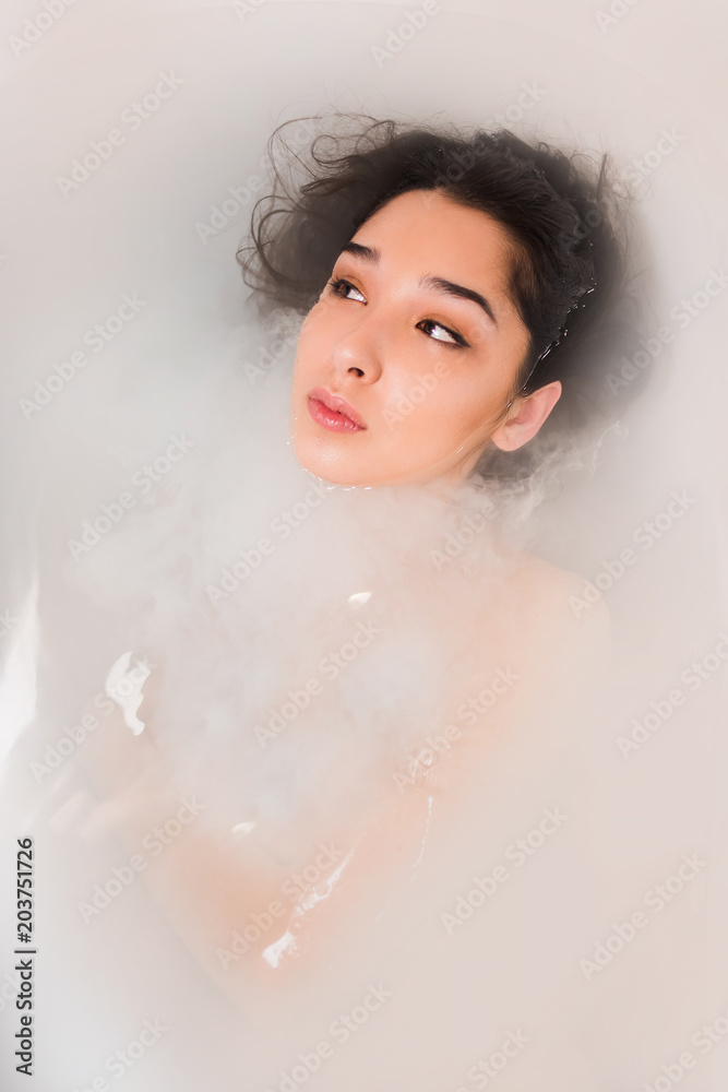 Woman looking away in white water in the bathroom, close up