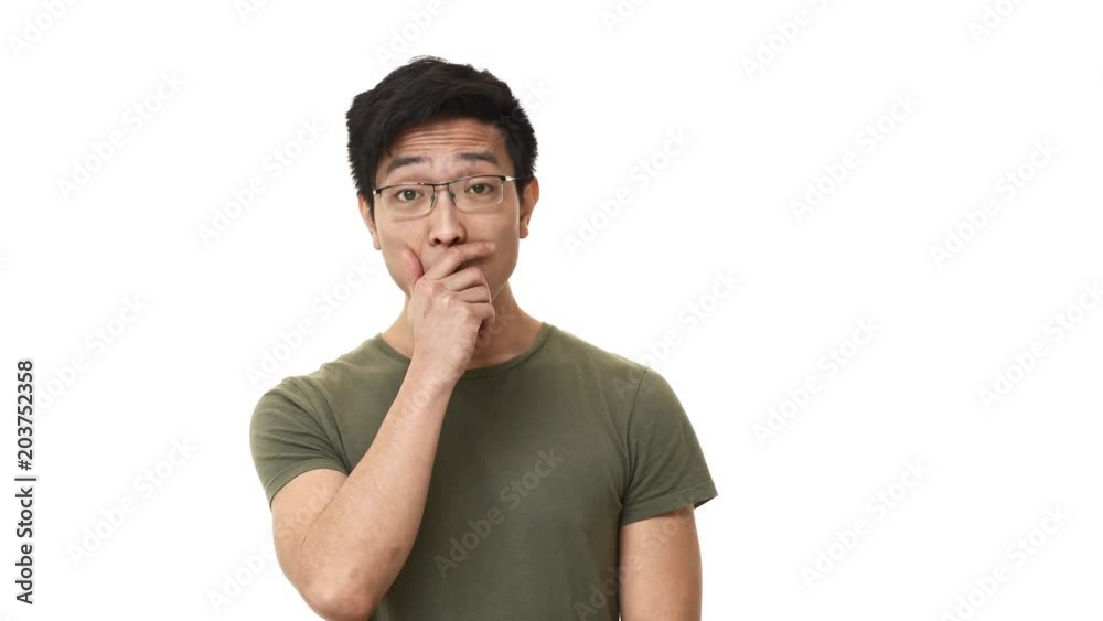 Portrait of concerned asian man 20s wearing glasses being shocked with unexpected news and covering open mouth in anxiety, isolated over white background. Concept of emotions Portrait of concerned asian man 20s wearing glasses being shocked with unexpected news and covering open mouth in anxiety, isolated over white background. Concept of emotions