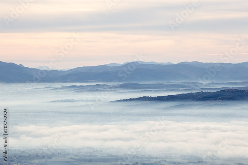 Beautiful aerial view of Umbria valley in a winter morning, with fog covering trees and houses © Massimo