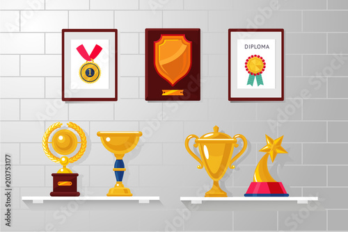 Trophy and awards collection on a white wall. Diplomas, competition prizes and cups.