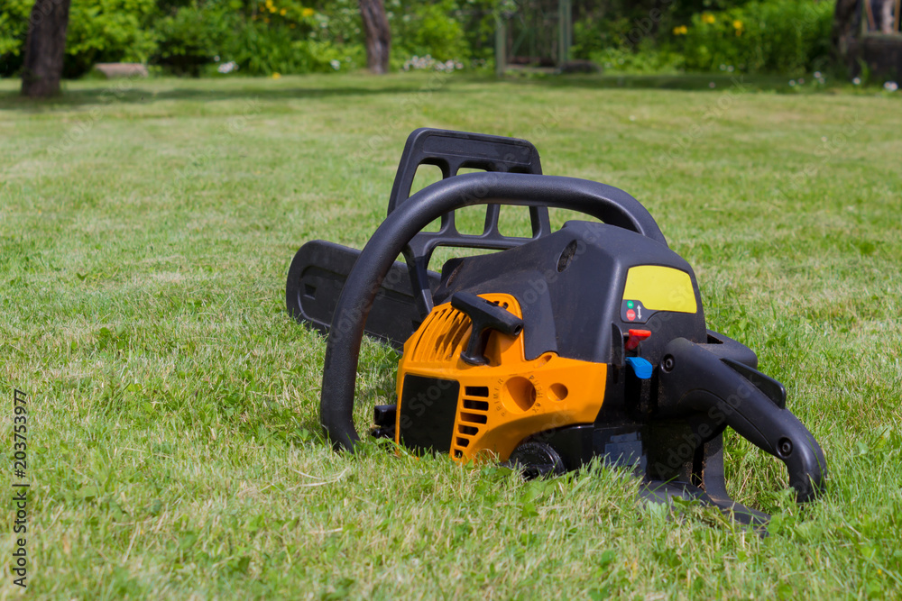 Fototapeta premium Black and orange chainsaw on grass