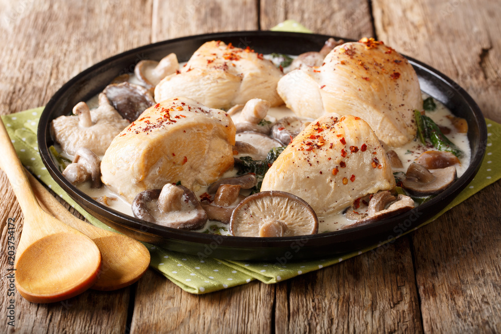 Natural food: stewed chicken fillets with wild mushrooms and spinach with gravy sauce close-up. horizontal