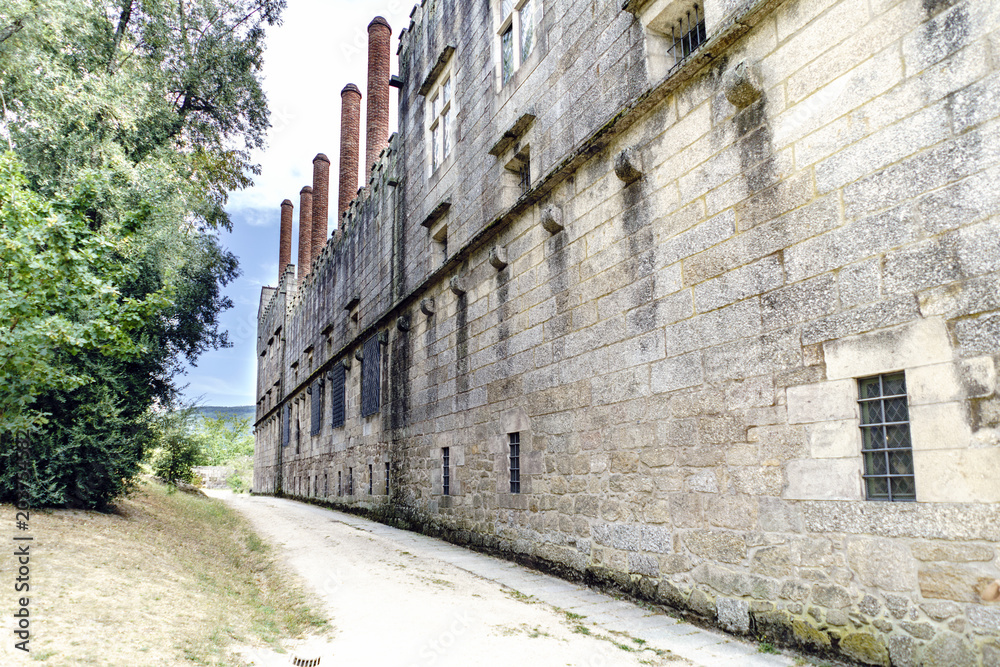 Exterior side of the palace of the Dukes of Braganza in Guimaraes (Portugal) with thick granite stone walls and large brick chimneys