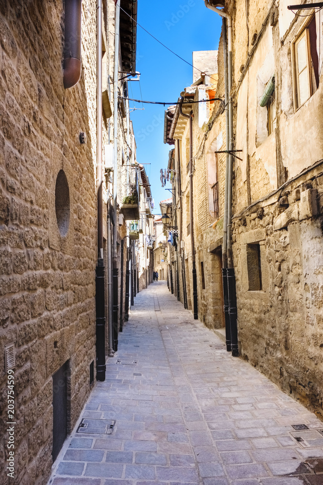 Narrow alley with floor of stone slabs and old houses of stone facades and iron balconies, typical of the north of Spain in the old part of the town called Laguardia in Alava (Spain)