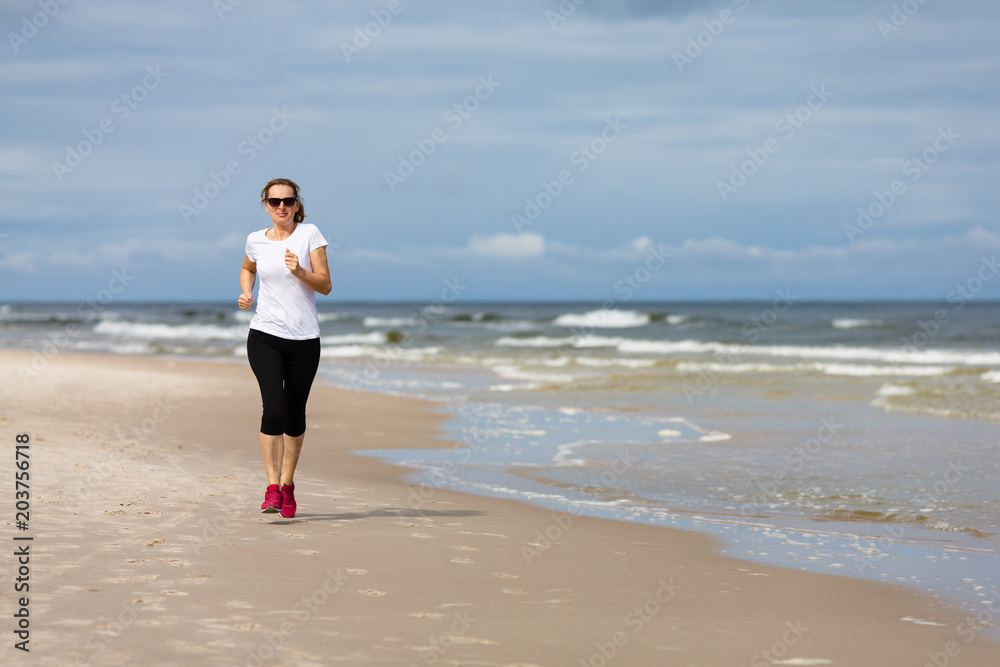 Middle-aged woman running on beach Middle-aged woman running on beach
