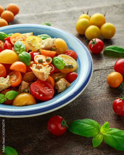 Homemade Panzanella  Tomato traditional Italian salad with red  yellow  orange cherry tomatoes  capers  basil and ciabatta croutons. summer healthy food.