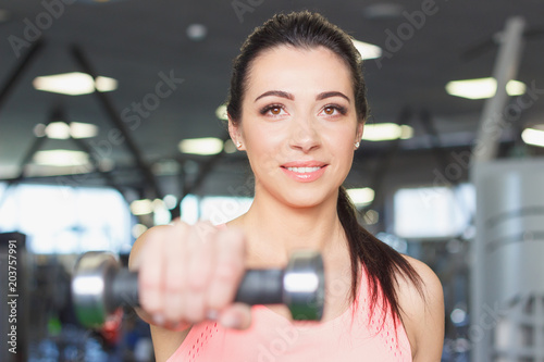 Sporty young woman with dumbbells in the hands