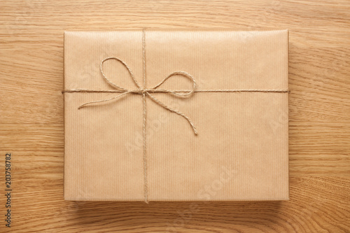 Big gift box wrapped in kraft paper on wooden table