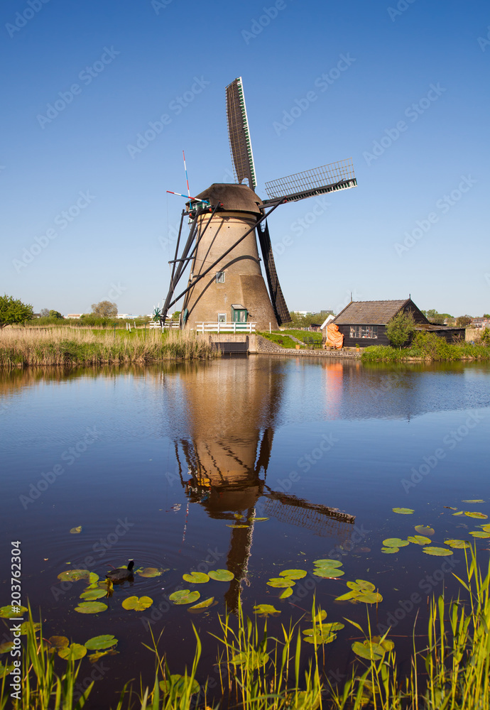 Traditional Dutch windmill reflected in the water of the canal i