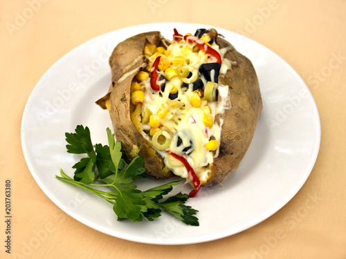 Baked kumpir potato stuffed with cheese, sausage, olives, peppers and corn photo