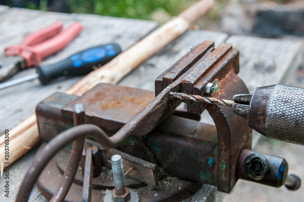 Piece of metal on the vise, hand operated drill press , focus on the iron chip. Piece of metal on the vise, hand operated drill press , focus on the iron chip.