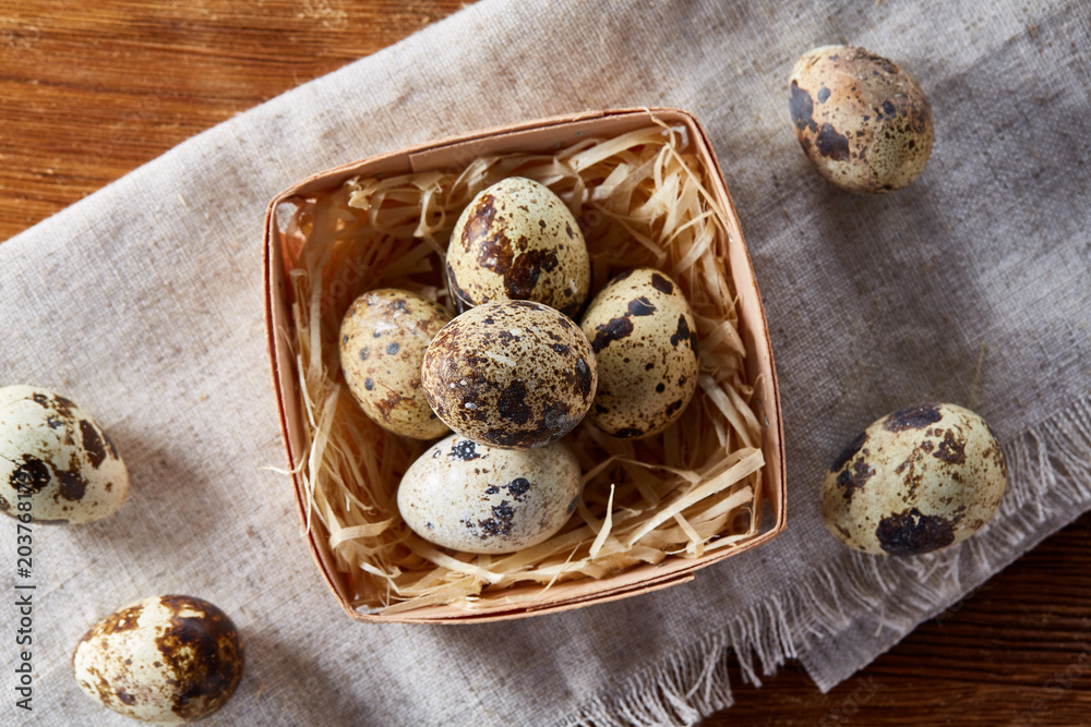 Quail eggs in a box on a rustic wooden background, top view, selective focus. Quail eggs in a box on a rustic wooden background, top view, selective focus.