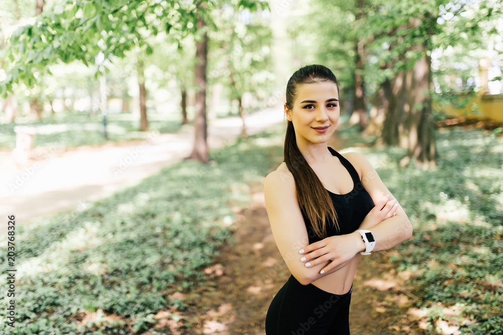 Portrait of smiling fit woman with hands folded standing at park Portrait of smiling fit woman with hands folded standing at park