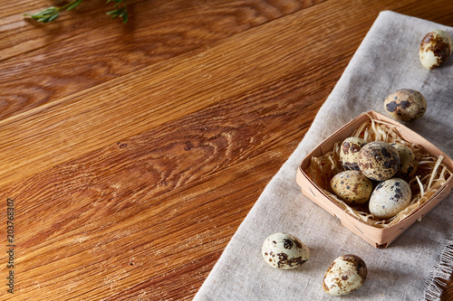 Quail eggs in a box on a rustic wooden background, top view, selective focus.