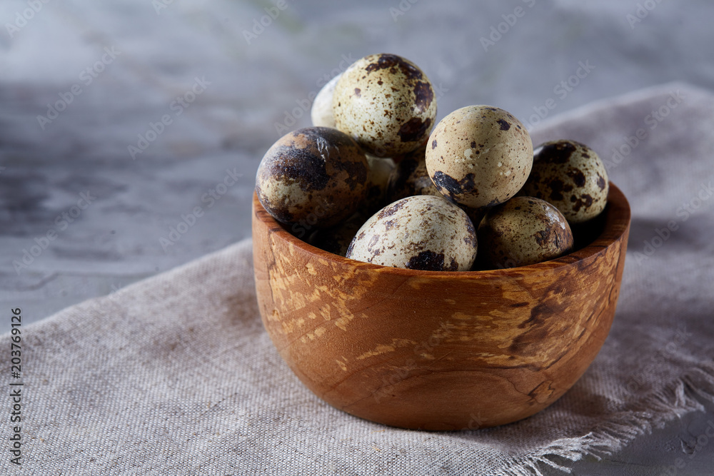 Bowl with eggs quail, eggs on a homespun napkin on grey background, close-up, selective focus Bowl with eggs quail, eggs on a homespun napkin on grey background, close-up, selective focus