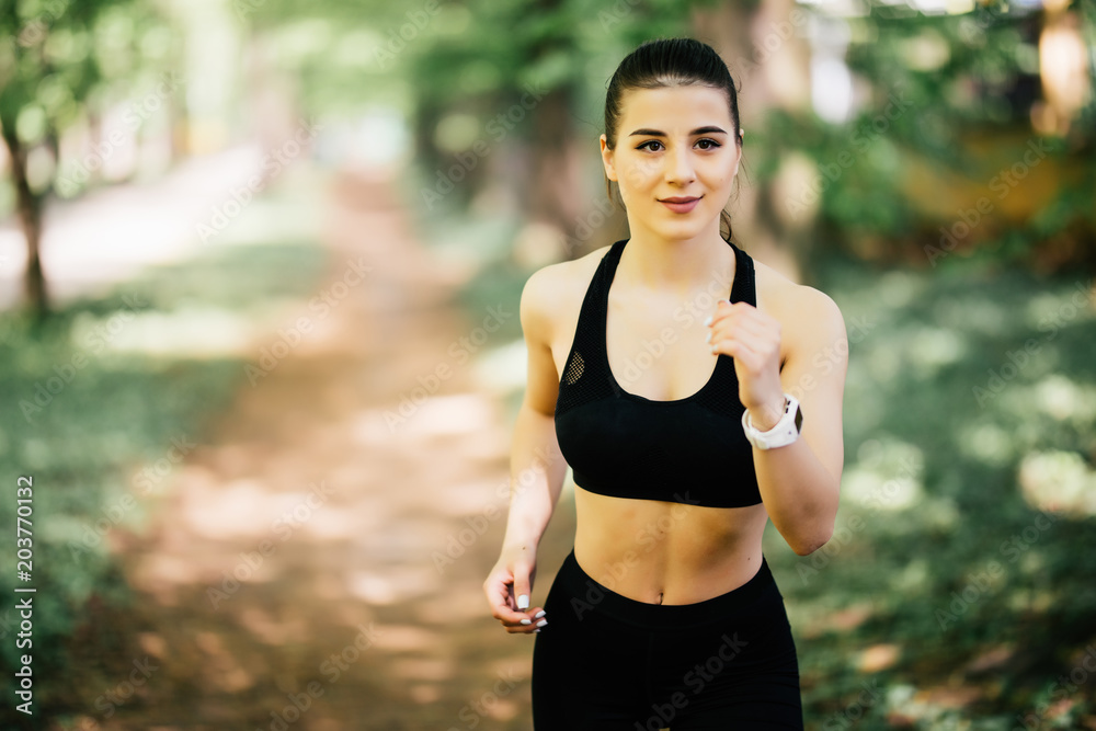 Fit young woman running in park outdoors Fit young woman running in park outdoors