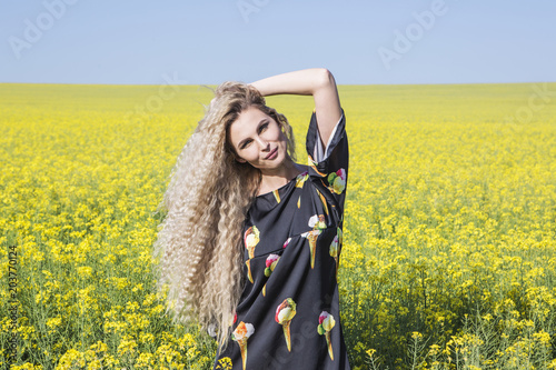 Portrait of a girl in yellow blooming field.