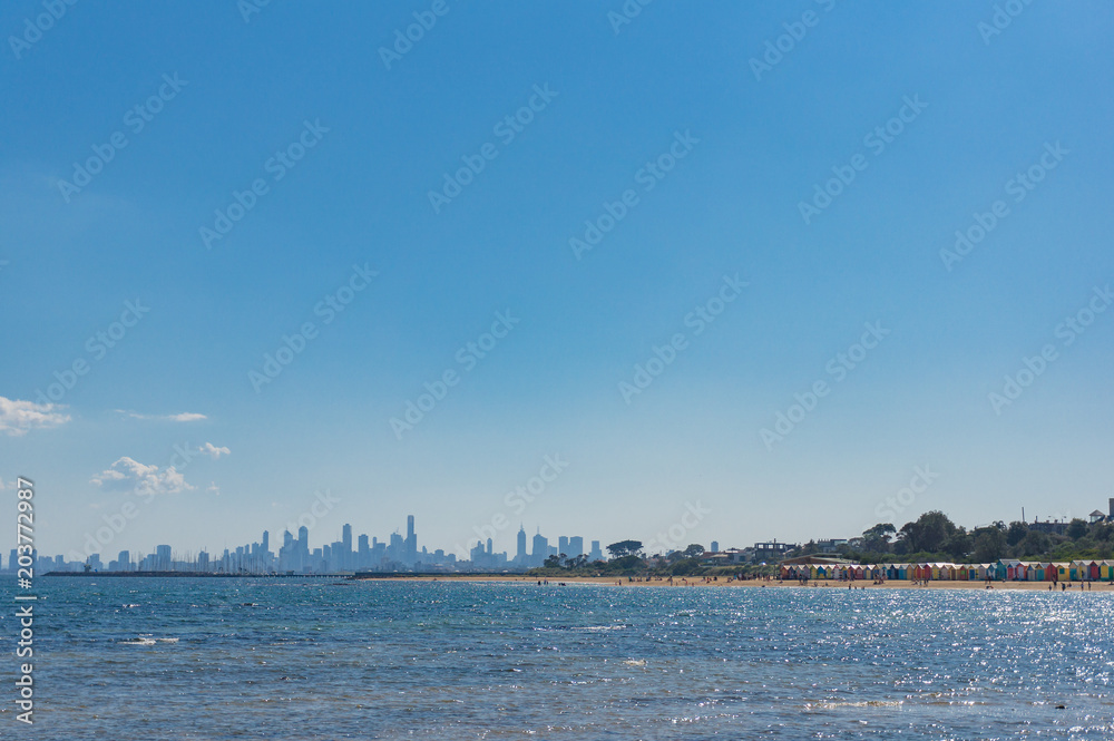 Sunny landscape with city skyline and beach with colorful beach houses in the distance